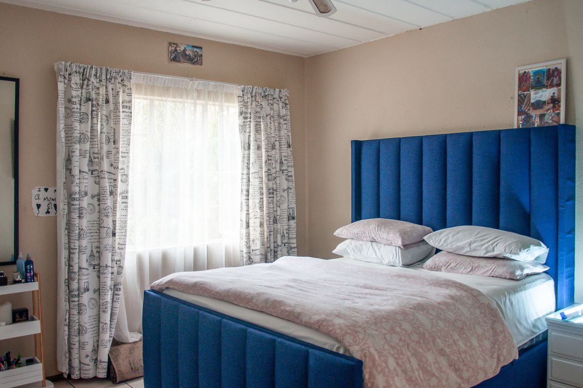 A well-lit bedroom featuring a large window with curtains and a ceiling fan, providing a comfortable and functional living space.