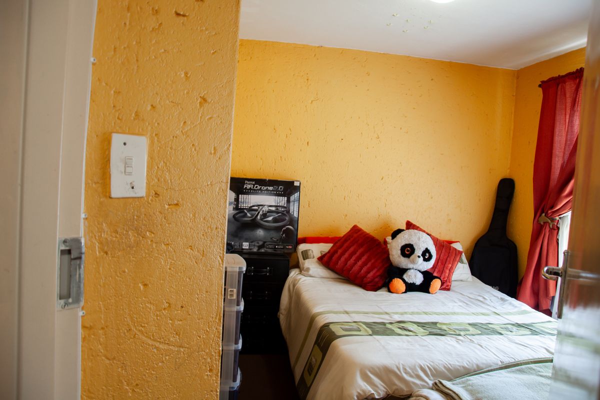 A bedroom featuring textured yellow walls and a window with red curtains.