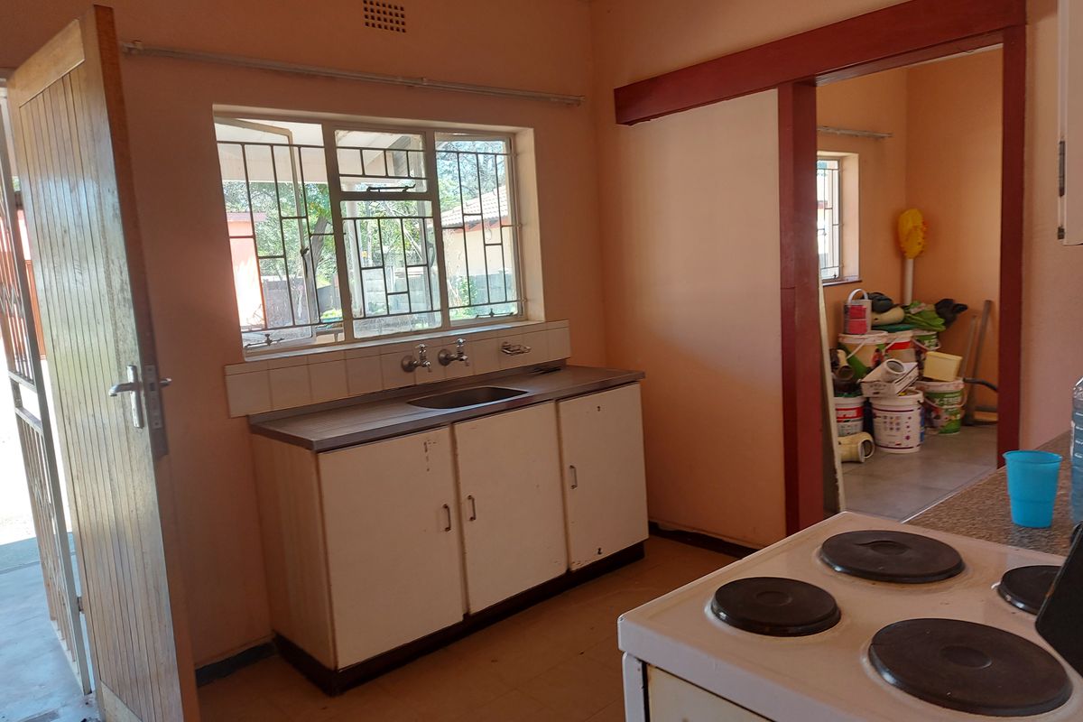 A functional kitchen space featuring built-in cabinetry, a stainless steel sink, and an electric stove, with an adjacent utility area visible.