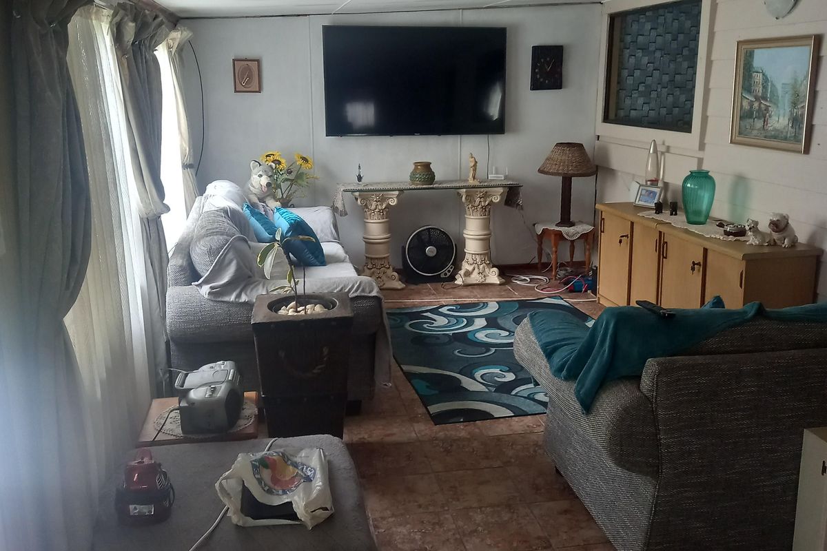 A living room featuring tiled flooring and a wall-mounted television, offering a functional space with potential for cosmetic updates to modernize the interior finishes.