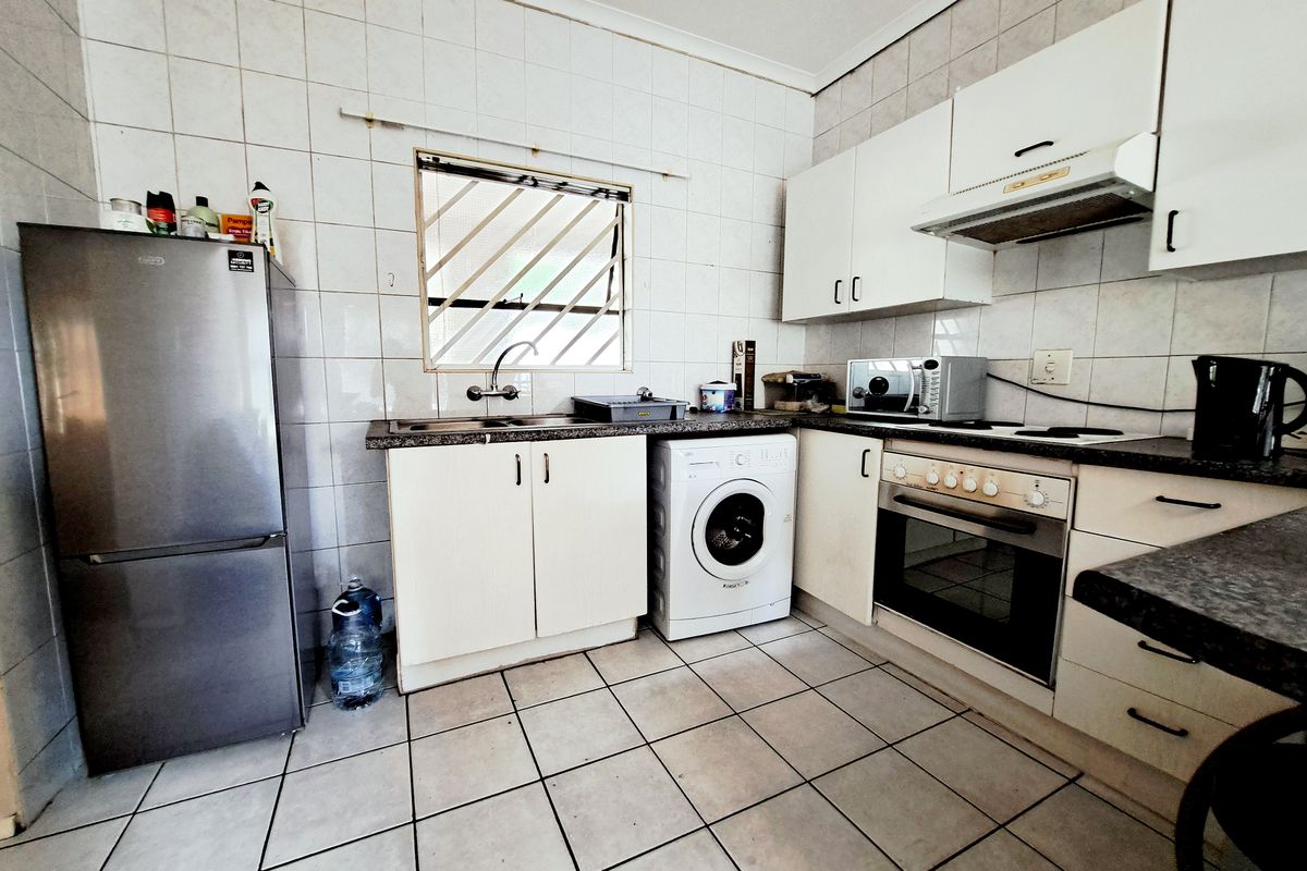 Functional kitchen featuring built-in cabinetry, integrated oven and hob, tiled splashbacks, and dedicated space for laundry appliances.