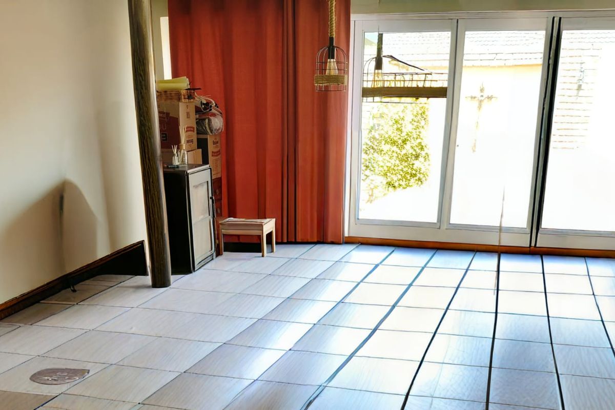A living area featuring tiled flooring and large sliding glass doors that provide direct access to the outdoor space.