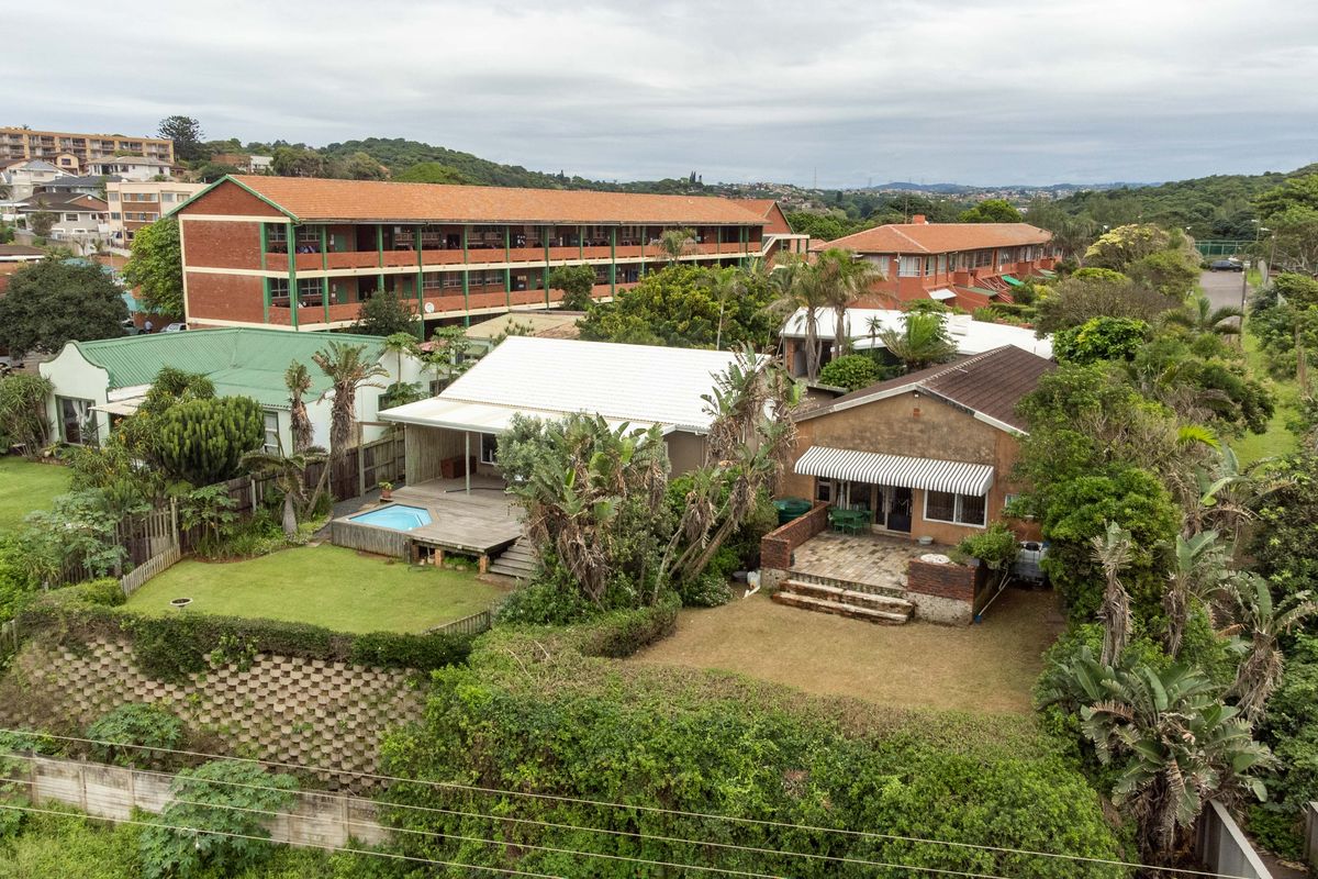 Aerial view of the property featuring a rear garden, swimming pool with wooden decking, and a paved patio area.
