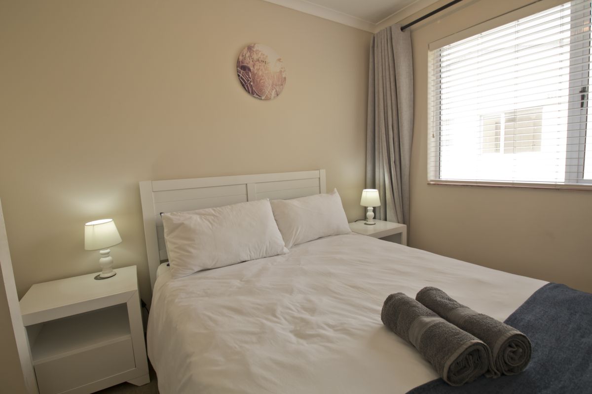 A well-maintained bedroom featuring neutral wall tones, a window with fitted blinds, and coved ceiling detailing.