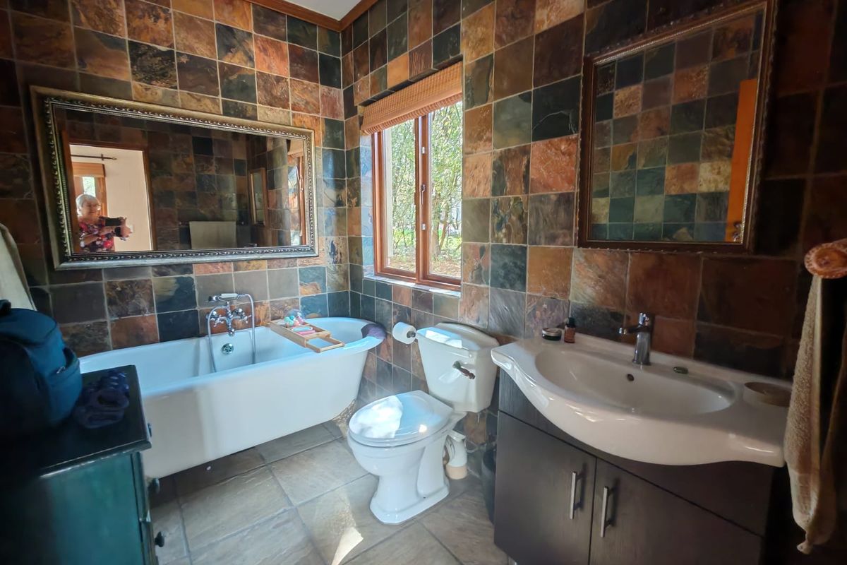 A bathroom featuring a freestanding bathtub, vanity cabinet with basin, and full-height slate wall tiling.