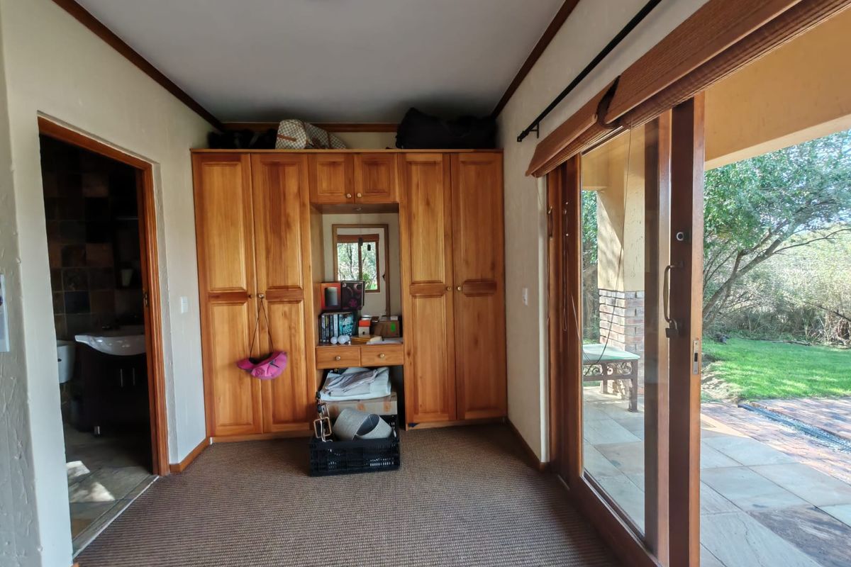 Bedroom featuring built-in wooden cabinetry and large sliding glass doors providing direct access to the outdoor patio and garden area.
