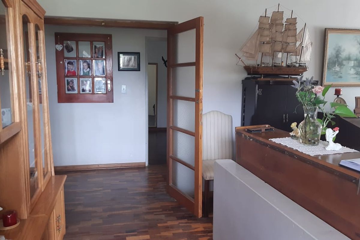 Interior view of a living area featuring parquet flooring, a wooden door frame, and a glass-paneled door leading to an adjacent room.