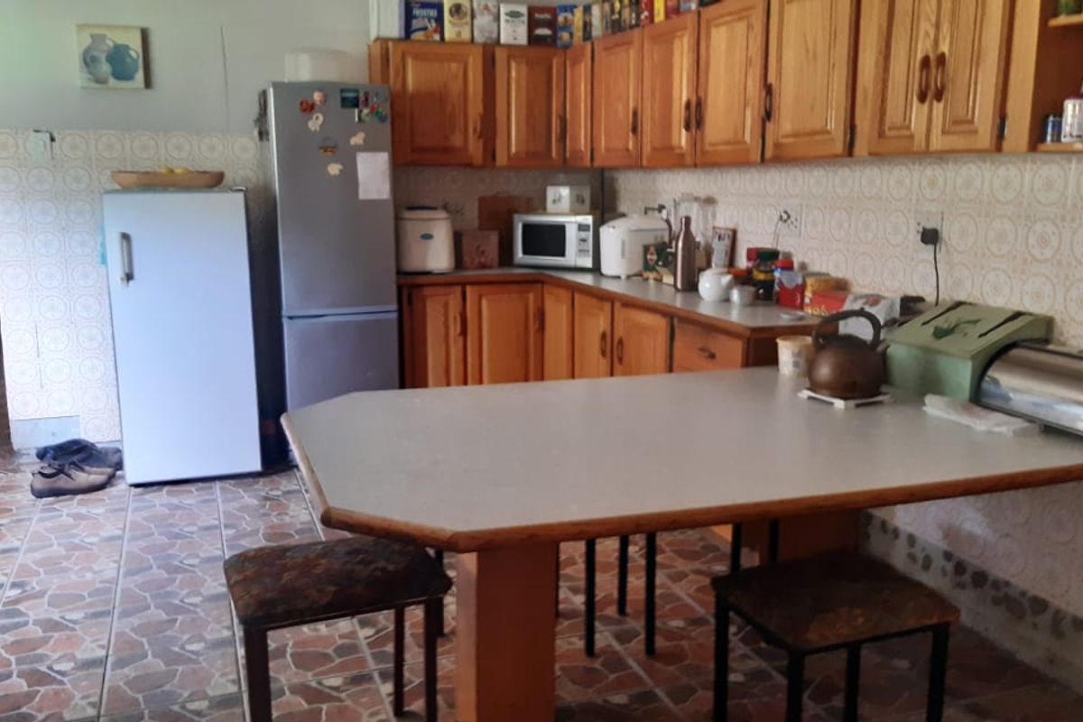 A dated kitchen featuring wooden cabinetry, tiled flooring, and a built-in breakfast counter, offering a functional layout with potential for modernization.