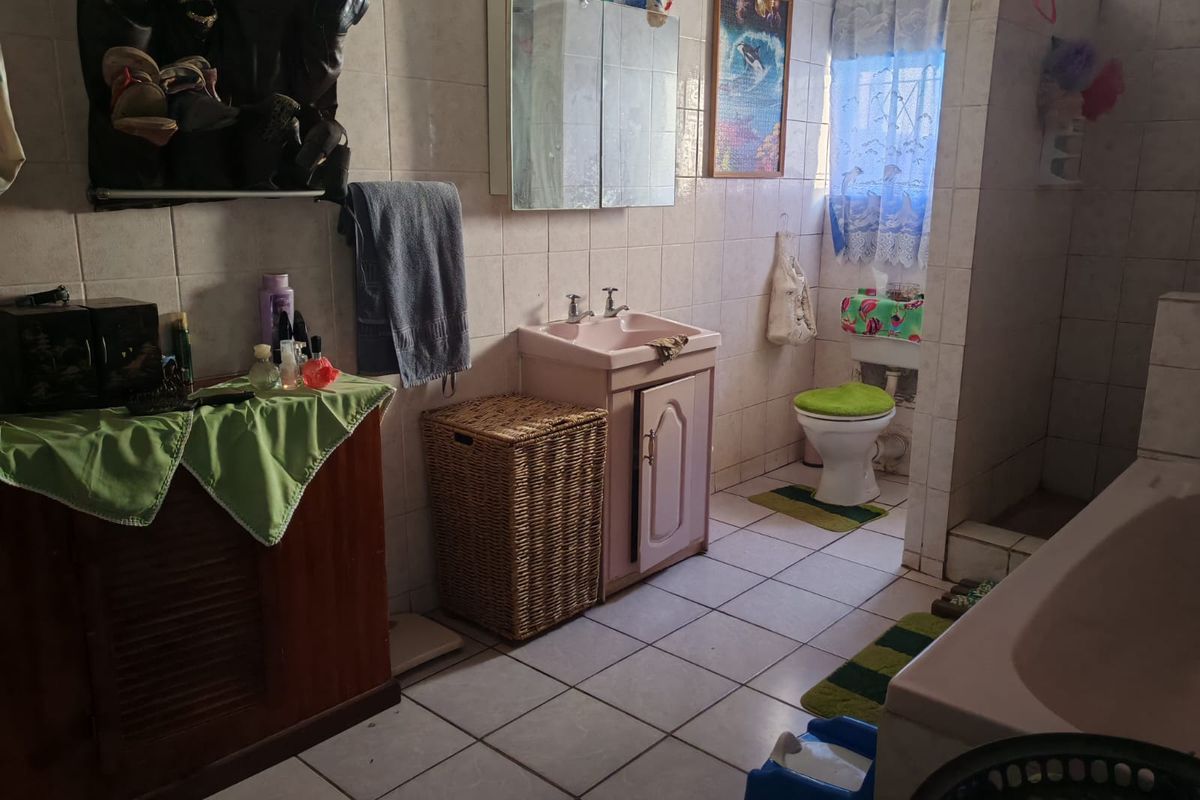 A functional bathroom featuring a vanity cabinet, basin, toilet, and bathtub with full-height wall tiling and floor tiles.