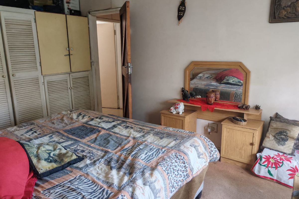 A bedroom featuring built-in cupboards and carpeted flooring, offering a functional space with potential for modernization.
