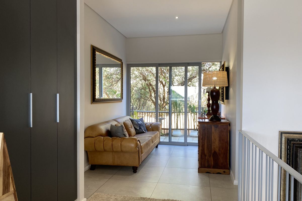A bright living area featuring large sliding glass doors, neutral tiled flooring, and built-in storage cupboards, offering a seamless transition to the outdoor space.