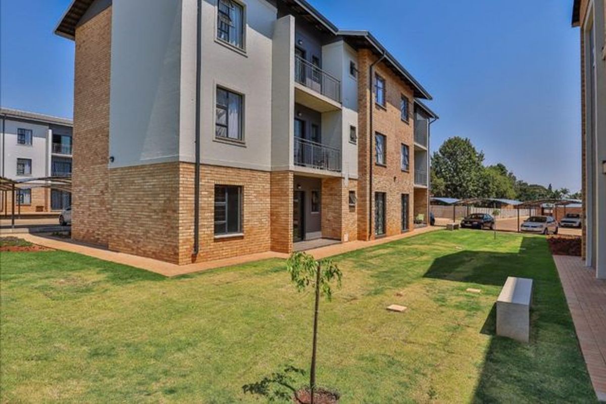 Exterior view of a modern apartment building featuring face-brick and rendered facade, private balconies, and well-maintained communal garden space.