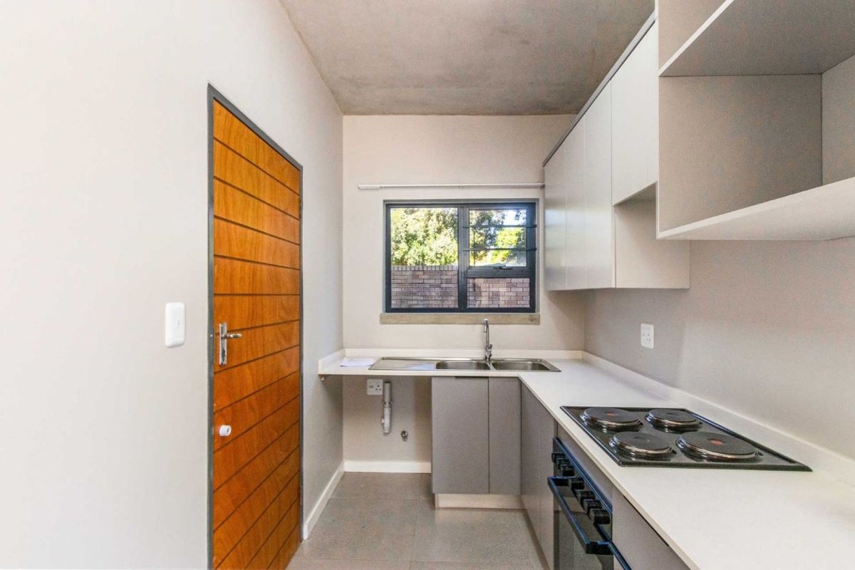 Modern kitchen featuring sleek cabinetry, a built-in electric hob and oven, stainless steel sink, and tiled flooring with a window for natural light.