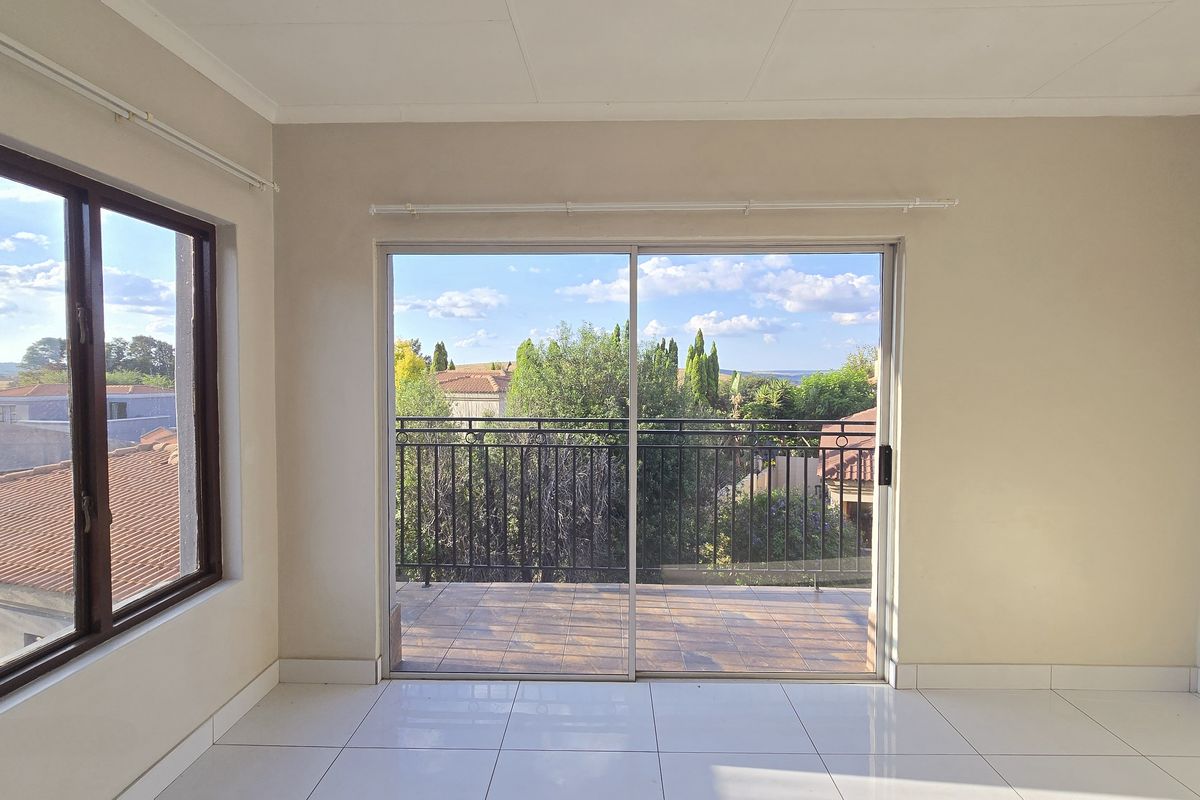 Bright and spacious living area featuring neutral walls, tiled flooring, and a large sliding glass door opening onto a private balcony with scenic views.