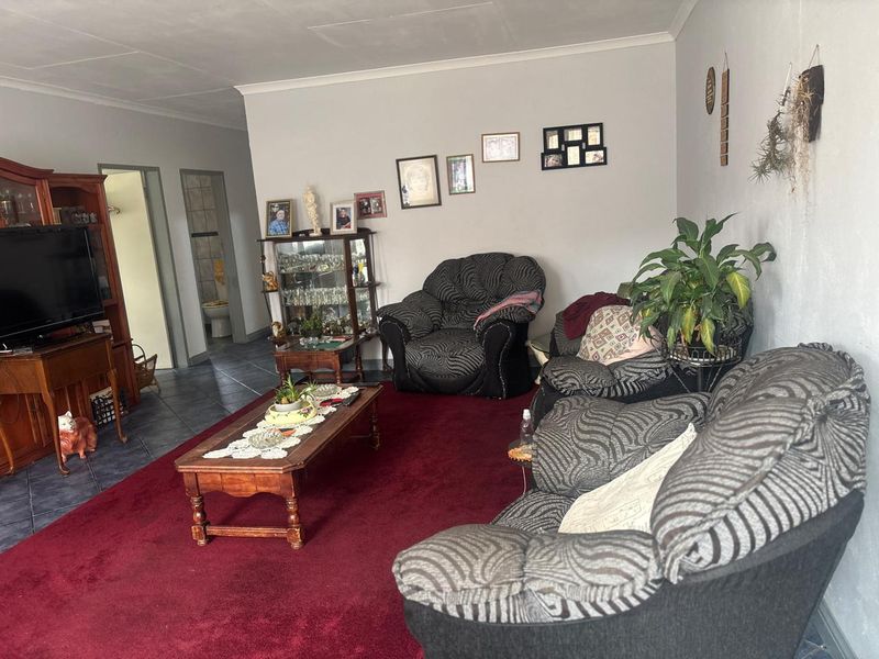 A spacious living room featuring tiled flooring, neutral wall finishes, and direct access to an adjacent bathroom area.