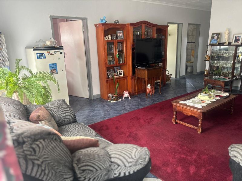 A living room area featuring dark tiled flooring, neutral wall finishes, and access to adjacent rooms.