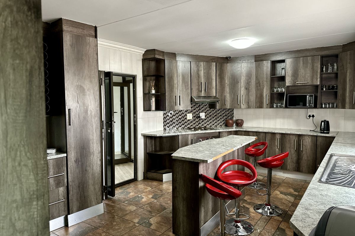 A well-appointed kitchen featuring dark wood-grain cabinetry, stone-look countertops, a breakfast bar, and a decorative hexagonal tile backsplash.