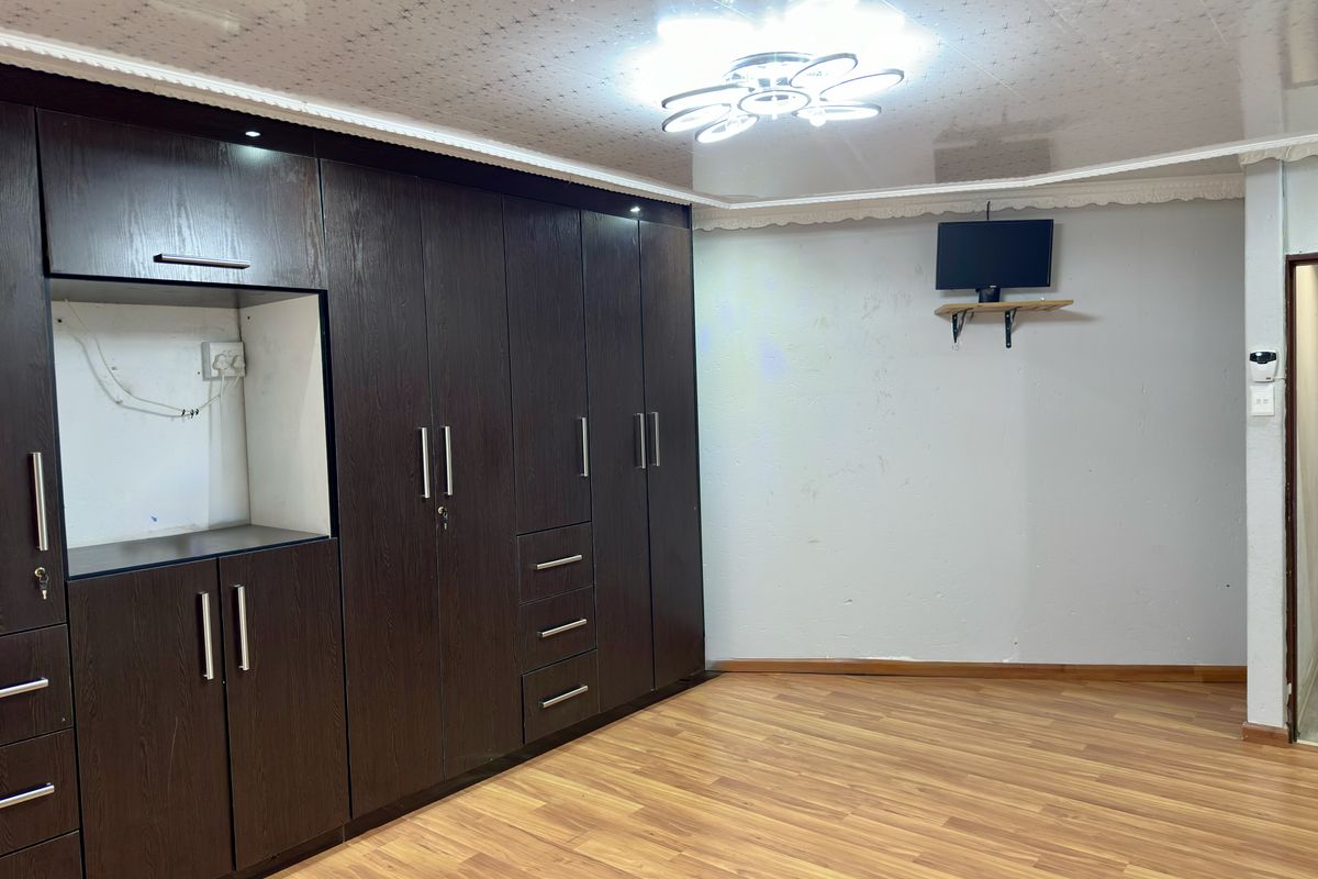 A bedroom featuring dark wood built-in cabinetry, laminate flooring, and a modern ceiling light fixture.