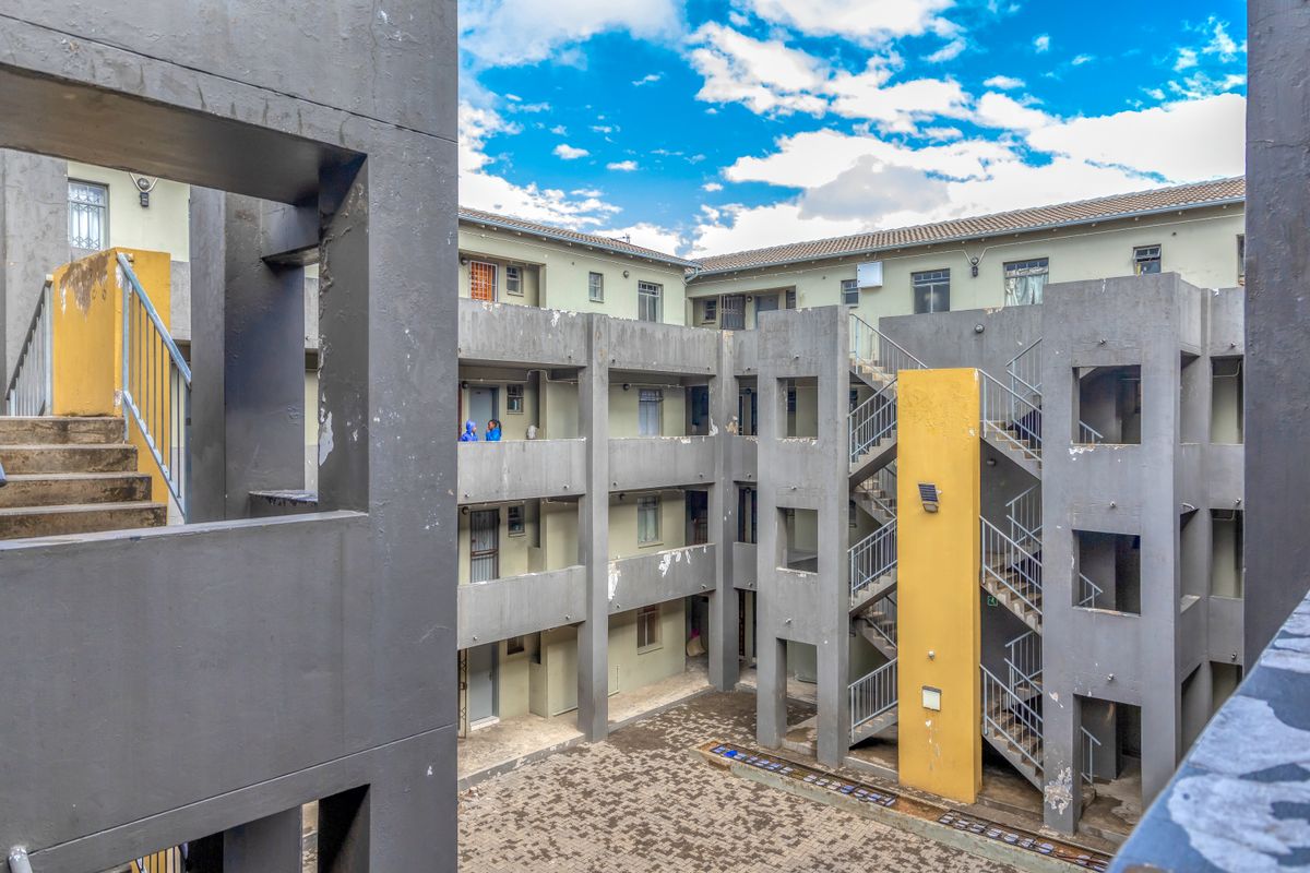 View of an apartment complex courtyard featuring concrete staircases, external walkways, and a paved ground level area.
