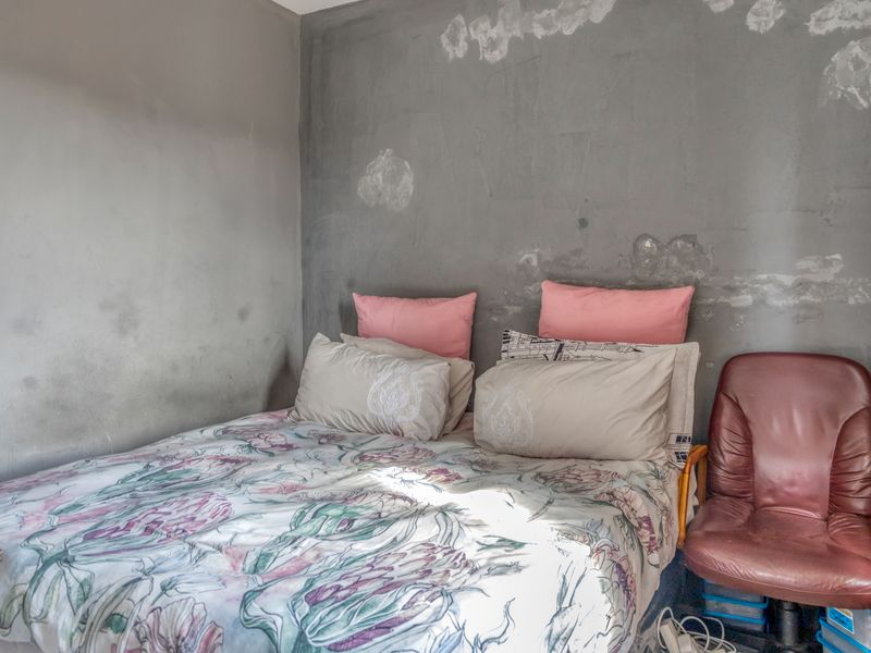 A bedroom featuring walls with significant surface damage and visible moisture staining, requiring repair and repainting to restore the space.