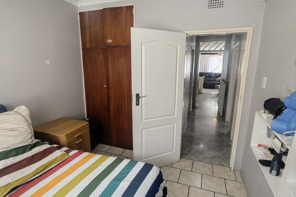 A bedroom featuring tiled flooring, a built-in wooden wardrobe, and direct access to the hallway.