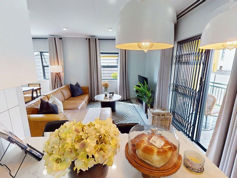 Modern open-plan living area featuring a sleek kitchen with quartz countertops, recessed lighting, and seamless flow to an outdoor patio through a security gate.