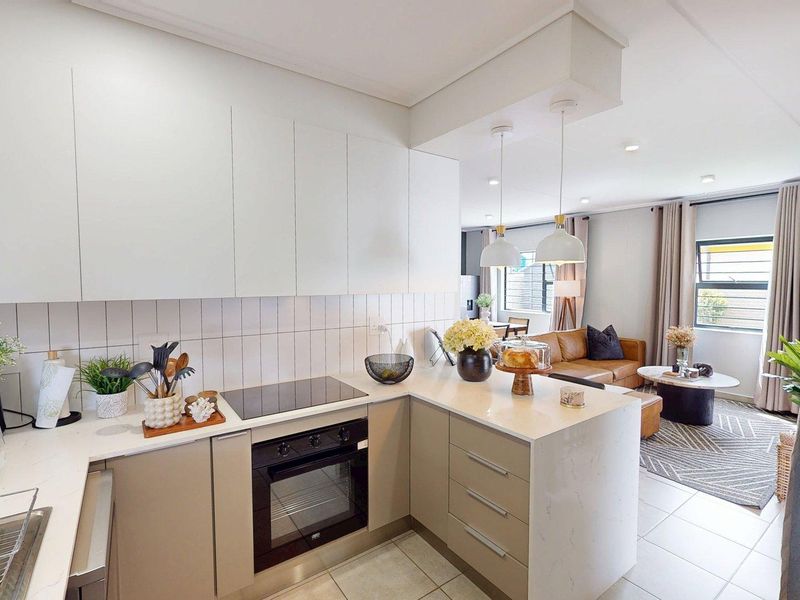 Modern open-plan kitchen featuring sleek cabinetry, stone countertops, integrated appliances, and a seamless flow into the adjacent living area.