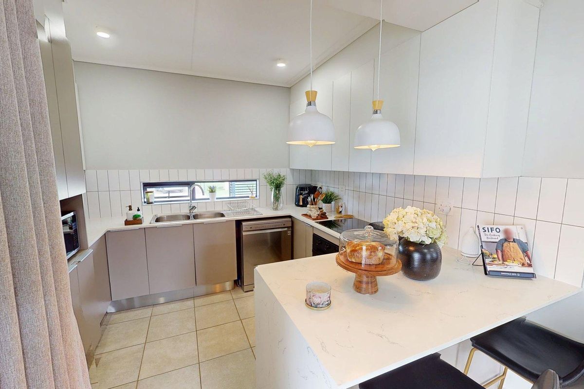 Modern kitchen featuring sleek built-in cabinetry, stone countertops, a tiled backsplash, and a functional breakfast bar island with pendant lighting.