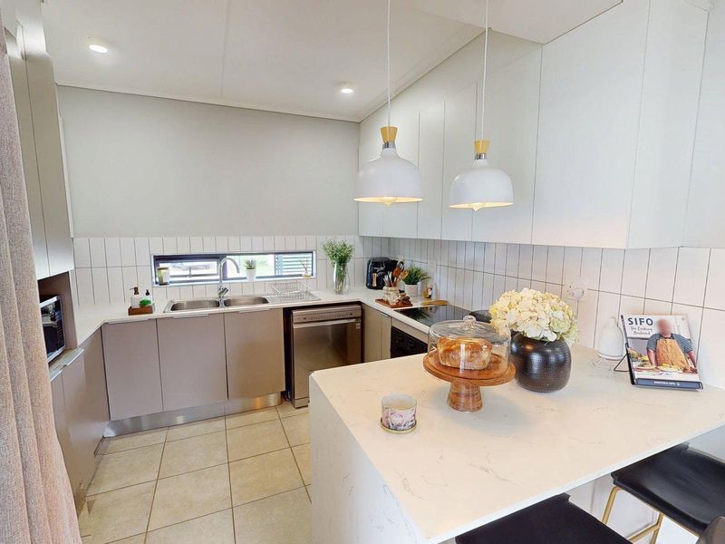 Modern kitchen featuring sleek built-in cabinetry, stone countertops, a tiled backsplash, and a functional breakfast bar island with pendant lighting.