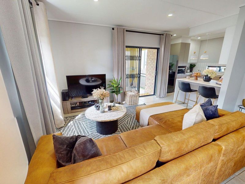 Modern open-plan living area featuring tiled floors, recessed lighting, and a seamless transition to the kitchen with a central island and built-in cabinetry.