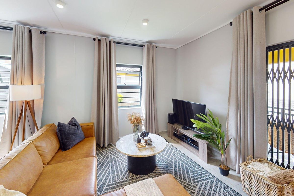 A bright and well-maintained living room featuring tiled flooring, recessed lighting, and a secure metal gate leading to an outdoor area.