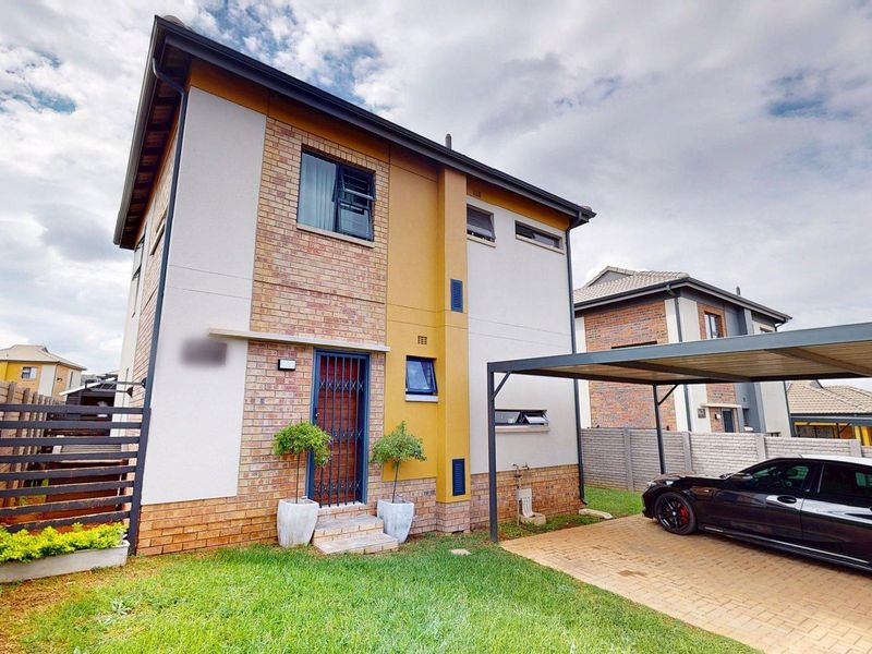 A modern two-story residential home featuring a brick and rendered facade, a private carport, and a paved driveway.