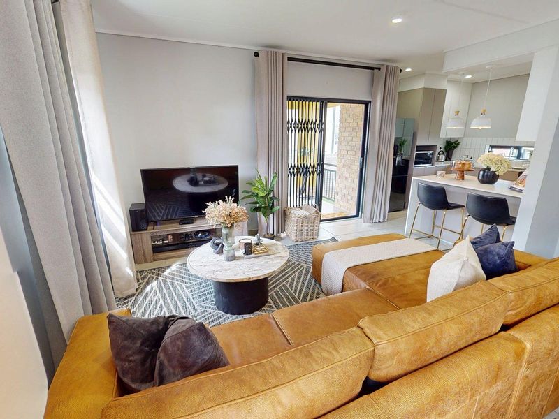 Modern open-plan living area featuring a kitchen island, tiled flooring, and seamless access to an outdoor patio through a sliding glass door.