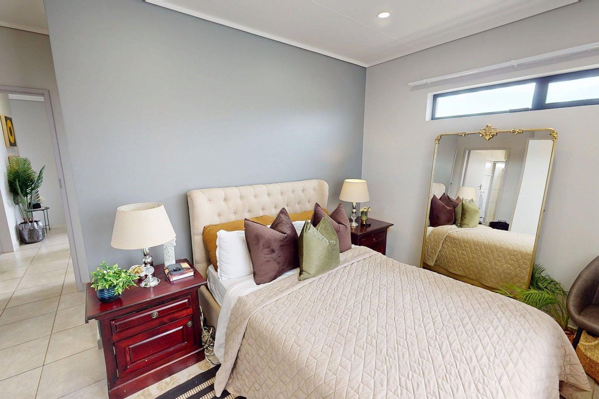 A well-maintained bedroom featuring neutral grey walls, a coved ceiling with recessed lighting, and a high-level clerestory window for natural light.