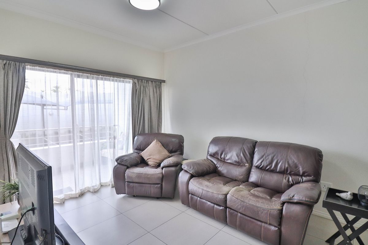 A living room featuring tiled flooring and a large sliding glass door providing access to an outdoor area.