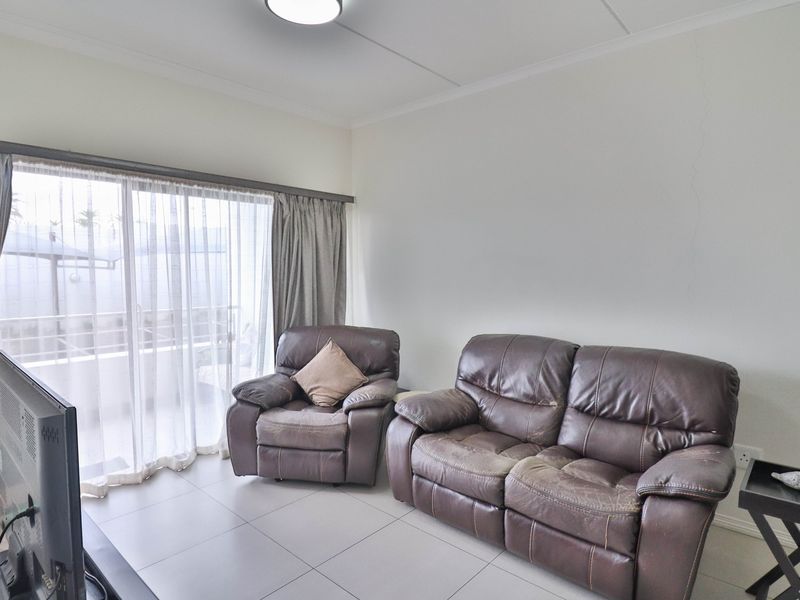 A living room featuring tiled flooring and a large sliding glass door providing access to an outdoor area.
