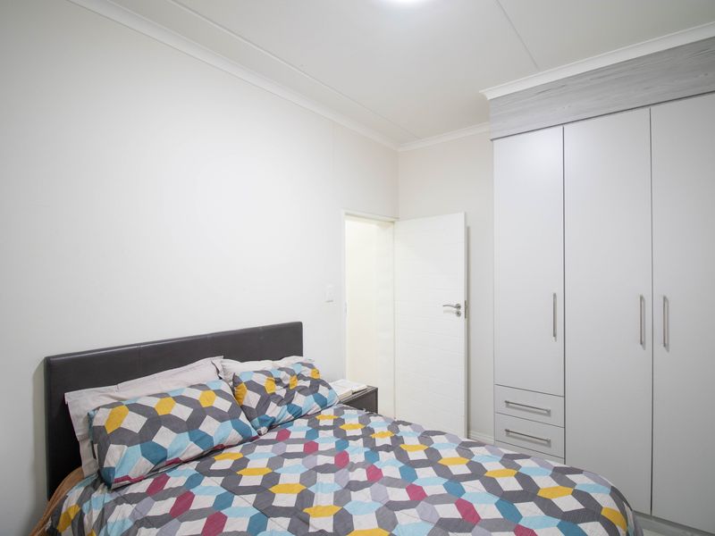 A well-maintained bedroom featuring a modern built-in wardrobe with integrated drawers and clean white finishes.