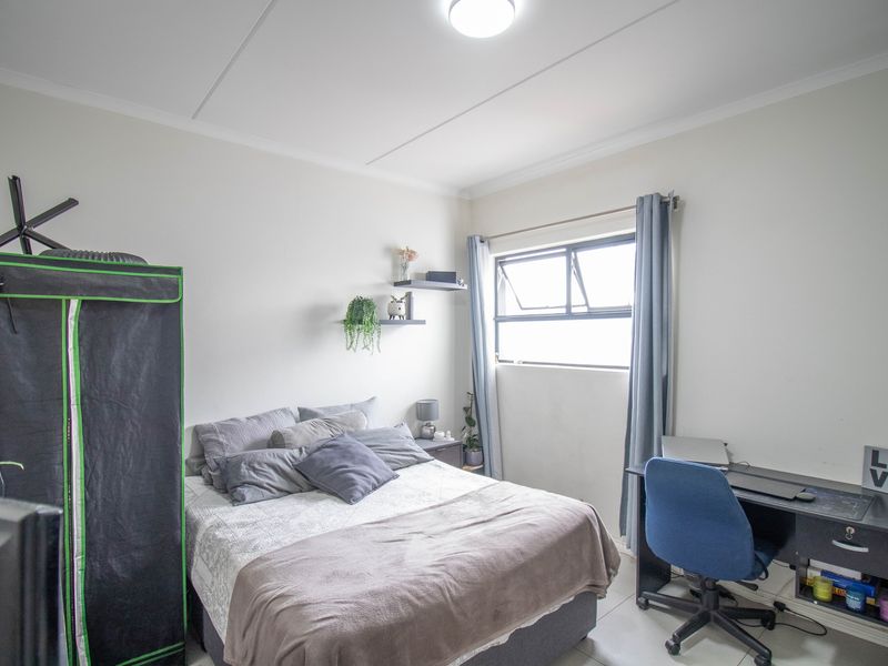 A functional bedroom featuring tiled flooring, a top-hung window, and neutral wall finishes, providing a comfortable space for rest or study.