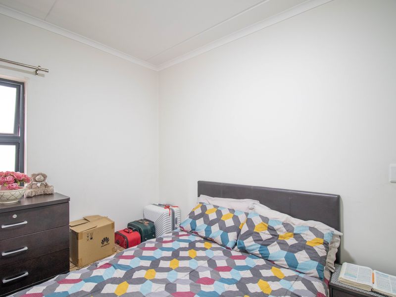 A functional bedroom featuring neutral walls, coving, and an aluminium window frame, providing a blank canvas for personalization.