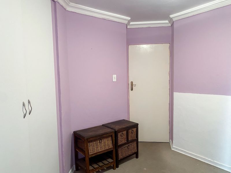 A bedroom featuring built-in cupboards, crown molding, and two-tone painted walls, offering a blank canvas for potential interior design updates.