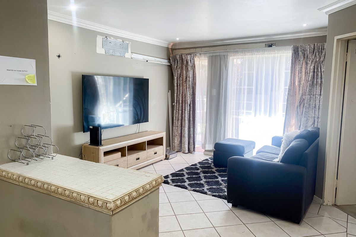A living room featuring tiled flooring, recessed lighting, and a tiled breakfast bar, with direct access to an outdoor area through sliding glass doors.