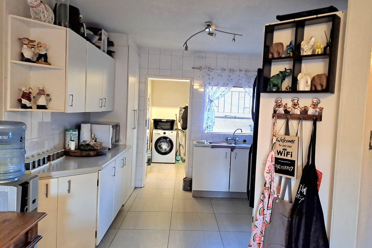 A functional kitchen featuring white cabinetry, tiled flooring, and a separate laundry area with plumbing for a washing machine.