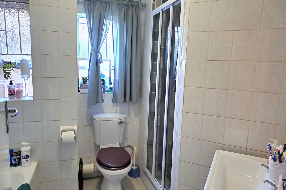 A functional bathroom featuring a shower enclosure, toilet, and basin with full-height wall tiling.