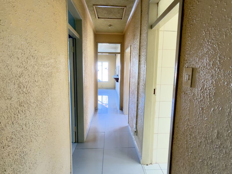 A functional hallway featuring tiled flooring and textured wall finishes, providing access to multiple rooms within the home.