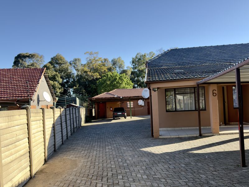 Front exterior view of the property featuring a paved driveway, carport, and precast boundary walling under a tiled roof.