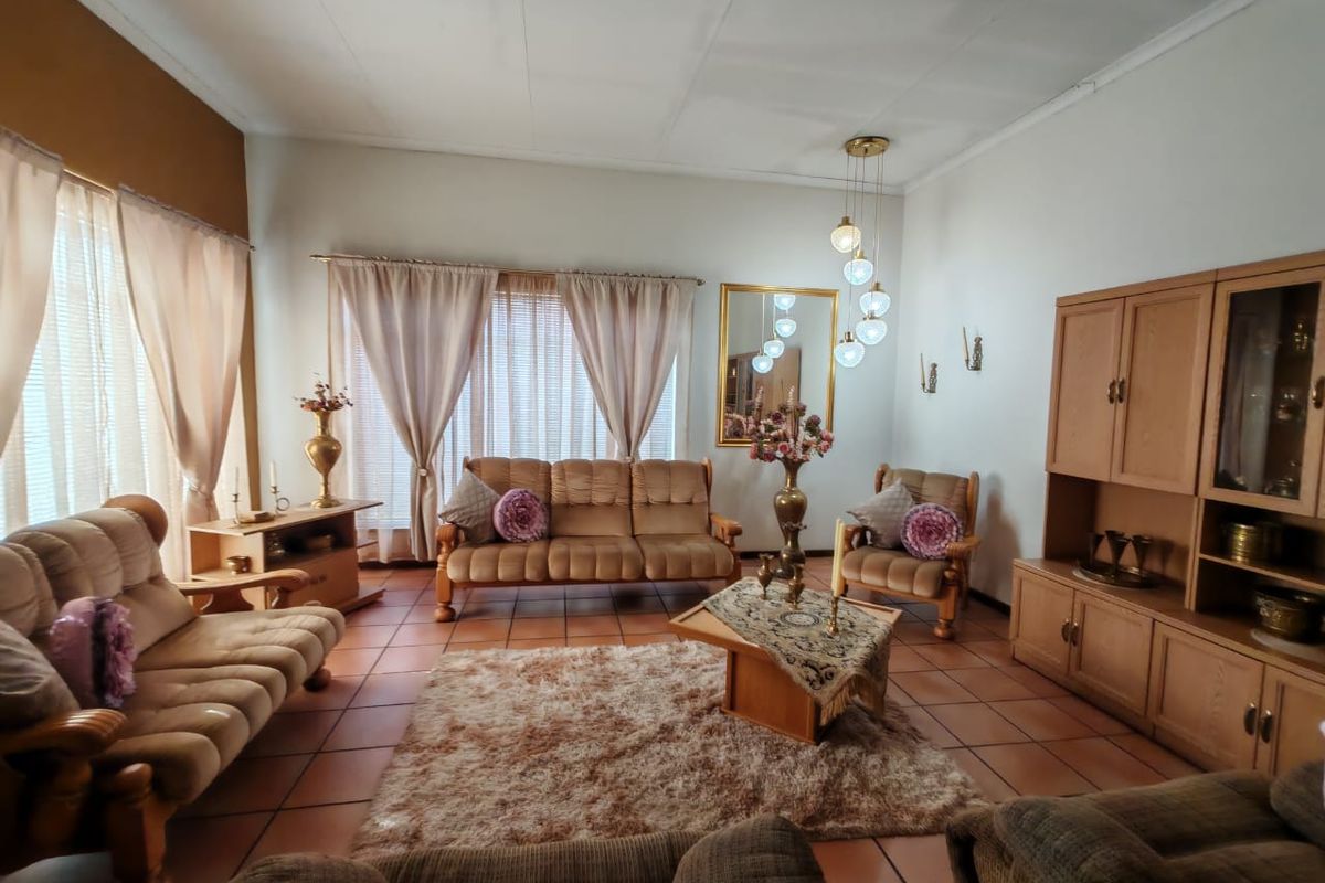 A spacious living room featuring tiled flooring, built-in cabinetry, and a multi-globe pendant light fixture.