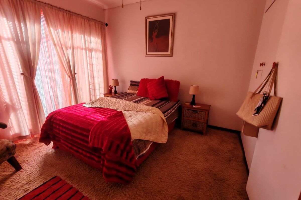 A bedroom featuring carpeted flooring and large windows with curtains, providing a functional space for rest.