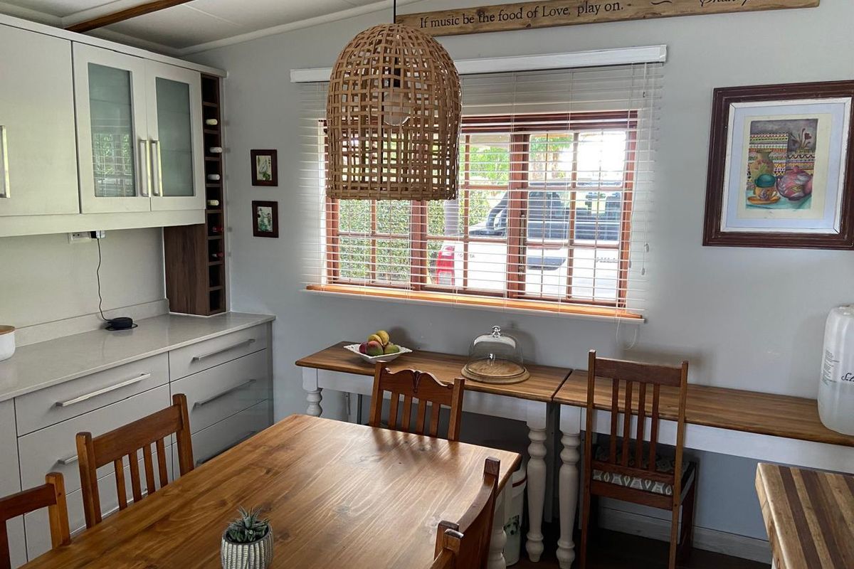 A well-maintained kitchen area featuring light-toned built-in cabinetry, stone countertops, and a functional window with venetian blinds.