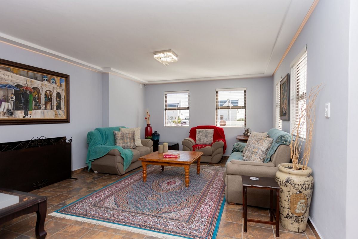 A comfortable living room featuring tiled flooring, recessed ceiling lighting, and multiple windows fitted with venetian blinds.