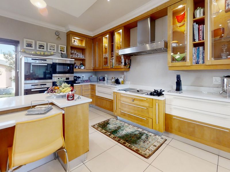 Modern kitchen featuring light wood cabinetry, stone countertops, integrated appliances, and a functional island layout with ample storage and workspace.